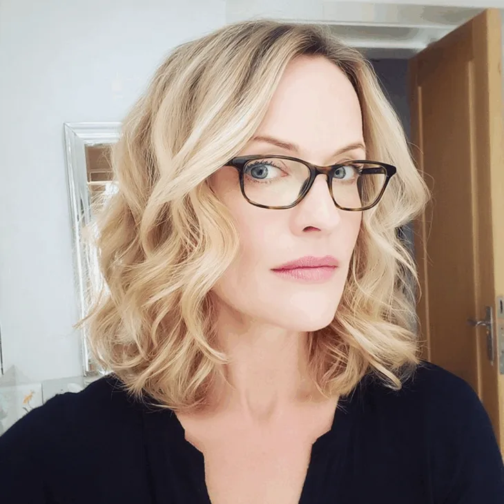 Best Hairstyles for Women Over 40 With Glasses That Are Anything but Boring Voluminous Blonde Curls with Side Part — Hairstyles for Women Over 40 with Glasses